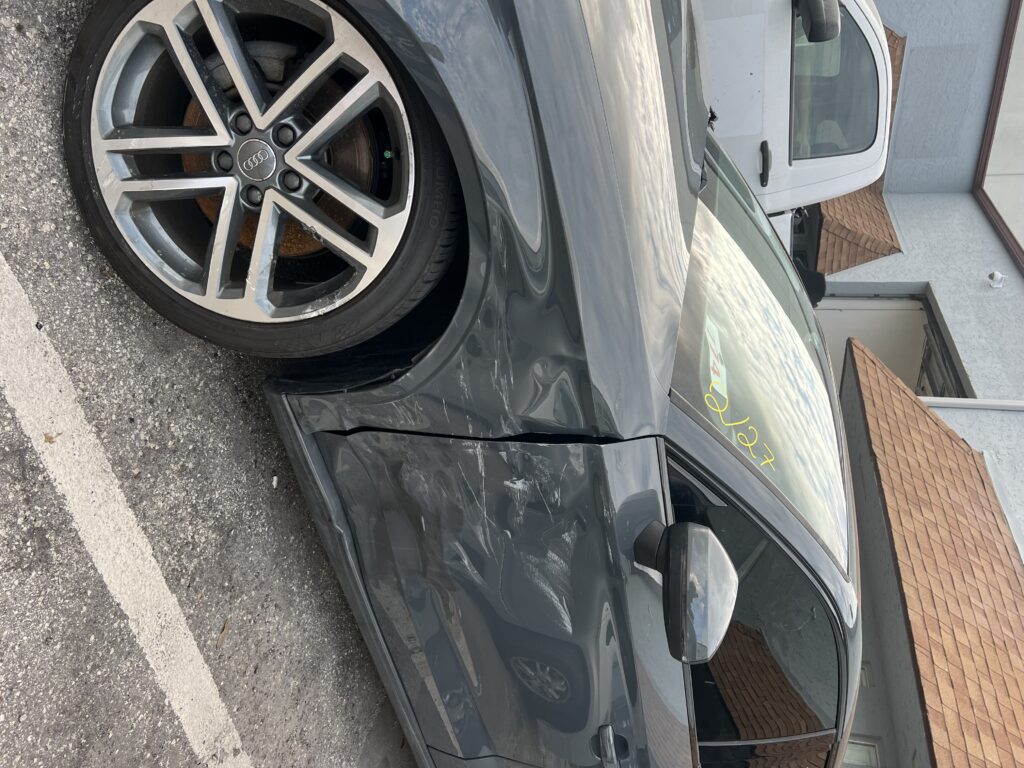 Car with collision damage showing dents and scratches before repair