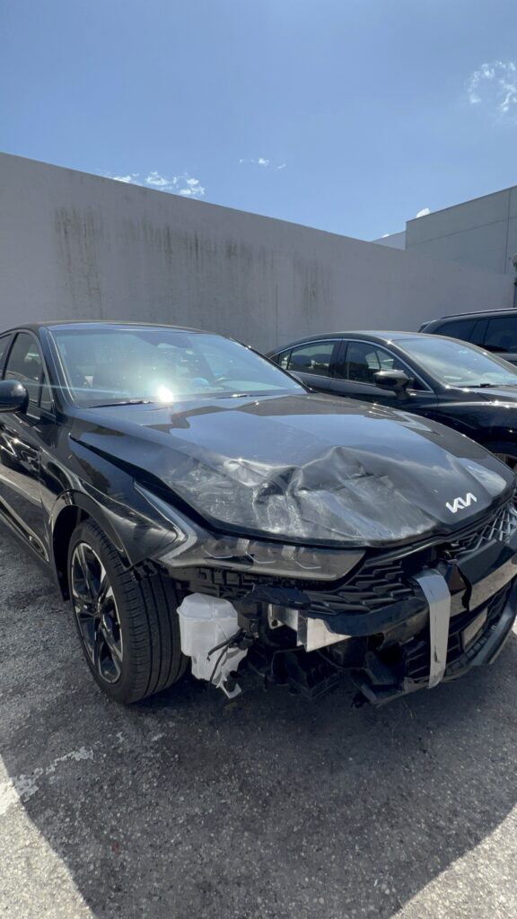 Vehicle with front-end collision damage including bent bumper and cracked headlight