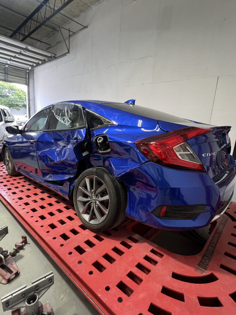 Vehicle showing damaged metal frame and misaligned panels before structural repair